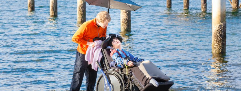 Disabled boy in a wheelchair on the beach