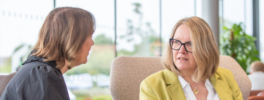 Alison Brooks talking to a colleague - 2 smartly dressed, professional-looking women